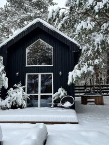 un edificio nero con neve per terra di Domki Wśród Boru Sosnowego, Śródborze a Julianów