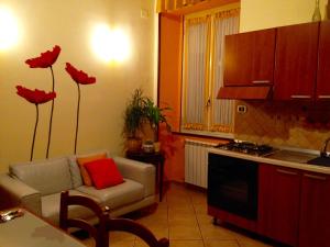 a living room with a couch and a kitchen with red flowers at Casina Tua Corso Novara in Naples