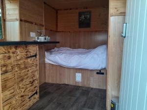 a small room with a bed in a wooden cabin at Belle's Belle-Vue in Thakeham