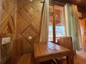 a wooden table in a room with a wooden wall at Jibhi Emberwood in Jibhi