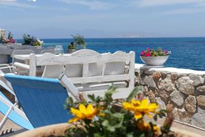 a blue chair sitting next to a stone wall with flowers at Kekrifalia Hotel in Skala