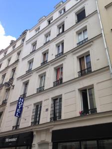a large white building with windows on a street at Hôtel Cyrano Voltaire in Paris