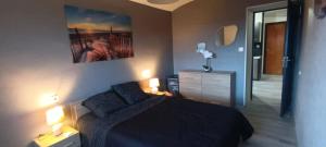 a bedroom with a black bed and two lamps at Gîte L'Olivier - Piscine partagée in Lagorce +10 photos