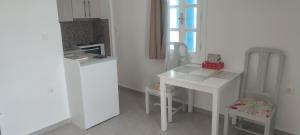 a kitchen with a white table and a white refrigerator at Filina's Studio Corner in Maltezana