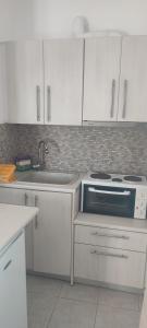 a kitchen with white cabinets and a sink and a stove at Filina's Studio Corner in Maltezana +17 photos