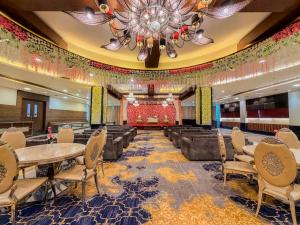 a banquet hall with tables and chairs and a chandelier at Spree Hotel Meerut in Meerut