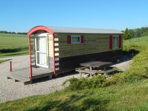 een kleine hut met een picknicktafel voor een veld bij Nuits Insolites d Argonne in Varimont