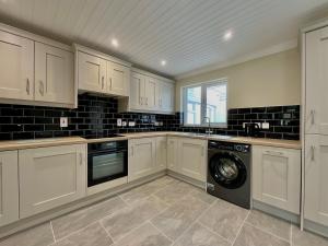 a kitchen with white cabinets and a washer and dryer at Apartment in Omagh in Omagh