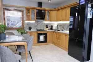 a kitchen with wooden cabinets and a black refrigerator at Садиба "Hutsulyana" in Yablunytsya