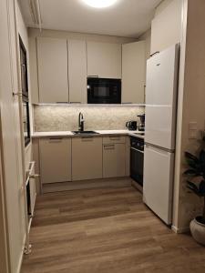 a kitchen with white cabinets and a white refrigerator at Kaupunkikoti omalla saunalla sekä lähellä juna-asemaa, 100M Wifi in Järvenpää