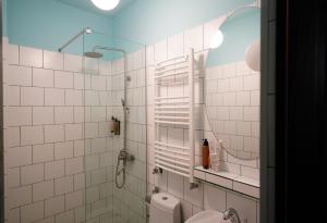 a white tiled bathroom with a shower and a toilet at Hotel Memoire Kutaisi in Kutaisi +92 photos