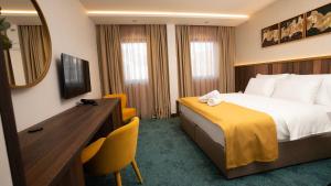 a hotel room with a bed and a desk and a mirror at Hotel Central in Inđija