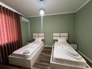 two beds in a small room with a window at Hotel, Bar, Restaurant Beni in Vlorë