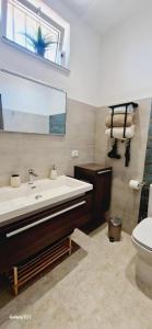 een badkamer met een wastafel, een toilet en een spiegel bij Terrazza Enjoy in Letojanni