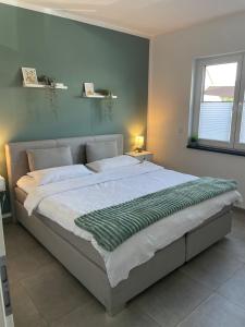 a bedroom with a large bed with a green blanket on it at Ferienwohnung in der wunderschönen Eifel in Dankerath