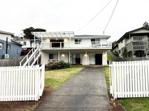 a white house with a white picket fence at Beside the Seaside Gerroa Dual Family Living in Gerroa