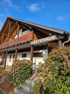 a building with a sign for a restaurant with flowers at Das Gästehaus Eimeldingen in Eimeldingen