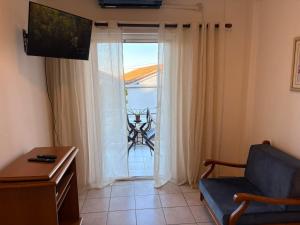 een woonkamer met een stoel en een glazen schuifdeur bij Port Breeze Apartment in Karlovasi