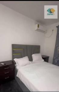 a bedroom with a white bed and a night stand at Appartement in Bonabéri