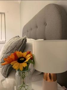 a vase with a flower on a table next to a bed at Pallister House Middlesbrough in Middlesbrough
