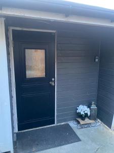 a black door with a window and a vase of flowers at Furnishe outhouse in Bergen +2 photos