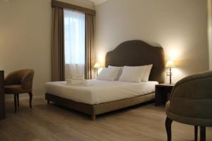 a bedroom with a bed and two chairs and a window at Hotel Hermes Tirana in Tirana