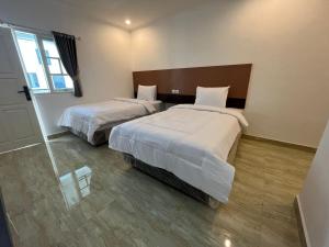 a hotel room with two beds and a window at The Royal Gisting - Heritage Hotel in Banjarnegeri