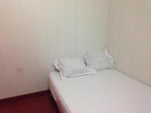 a small room with a bed with white sheets and pillows at Hôtel Cyrano Voltaire in Paris