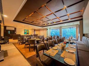 a restaurant with tables and chairs and a large window at Spree Hotel Meerut in Meerut