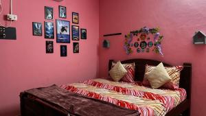 een slaapkamer met een bed met een roze muur bij Maison De Ravi in Pondicherry