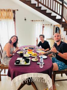 een groep mensen die rond een tafel zitten met eten bij Namal Guest House in Dikwella +35 foto's