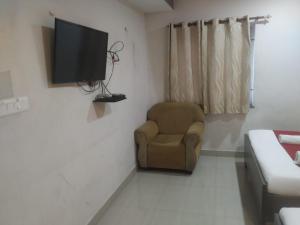 een woonkamer met een stoel en een flatscreen-tv bij VRJ Residency inn in Chennai +10 foto's