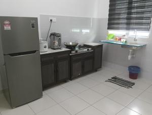 a kitchen with a refrigerator and a counter top at Homestay Gapam Kasih in Bemban