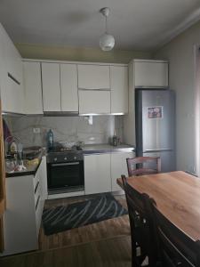 a kitchen with white cabinets and a table and a refrigerator at Kristina Guesthouse in Librazhd