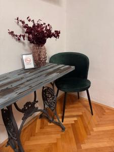 a table and a green chair with a vase of flowers at Tri srca 2 - De Luxe 2 in Trebinje +9 photos
