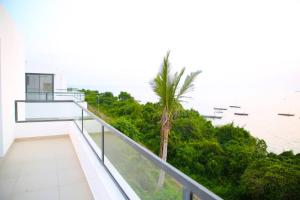 a balcony with a view of the ocean and a palm tree at Bustani Villa in Mchamba Wima