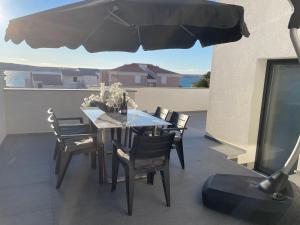 a table and chairs on a balcony with an umbrella at Second home apartment - silver in Kustići