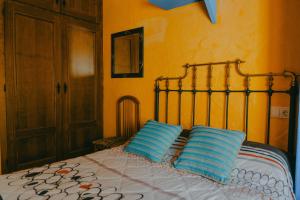 een slaapkamer met een bed met twee blauwe kussens bij La Huella del Cuero in Siles