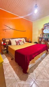 a bedroom with a large bed with an orange wall at Casa Refúgio Cataratas by Grasi in Foz do Iguaçu