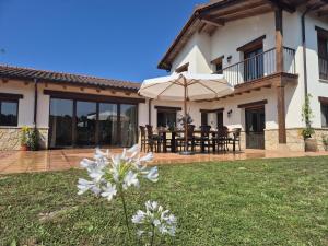 a house with a patio with tables and umbrellas at Casa Eloy in Argüero