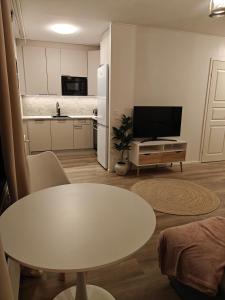 a living room with a white table and a kitchen at Kaupunkikoti omalla saunalla sekä lähellä juna-asemaa, 100M Wifi in Järvenpää
