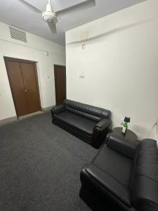 a room with two black leather couches and a wall at Lake Circus Heritage in Dhaka +1 photo