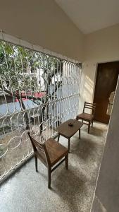 a balcony with two chairs and a table and a window at Lake Circus Heritage in Dhaka