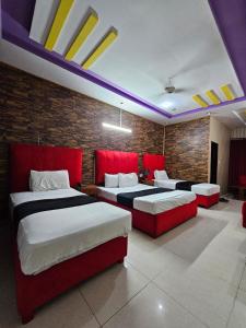 two beds in a room with red and white at Hotel Tulip INN in Lahore