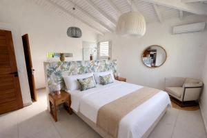 a white bedroom with a large bed and a chair at Villa Cokoon in Saint-François