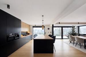 a kitchen and dining room with black cabinets and a table at Willa Black Wood in Istebna