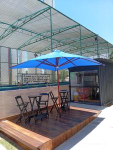 a table and chairs under a blue umbrella on a deck at Apto térreo com área privativa ! in Rio das Ostras