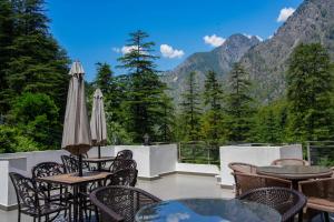 balcone con tavoli, sedie e vista sulle montagne di HUKAM'S HOLIDAY HOME by HHH a Kasol