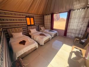 two beds in a room with a view of the desert at Starry Nights Luxury Camp in Wadi Rum +30 photos