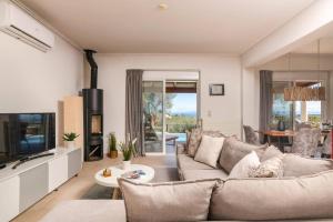 a living room with a couch and a tv at Villa Gisele with Private Pool in Tragaki
